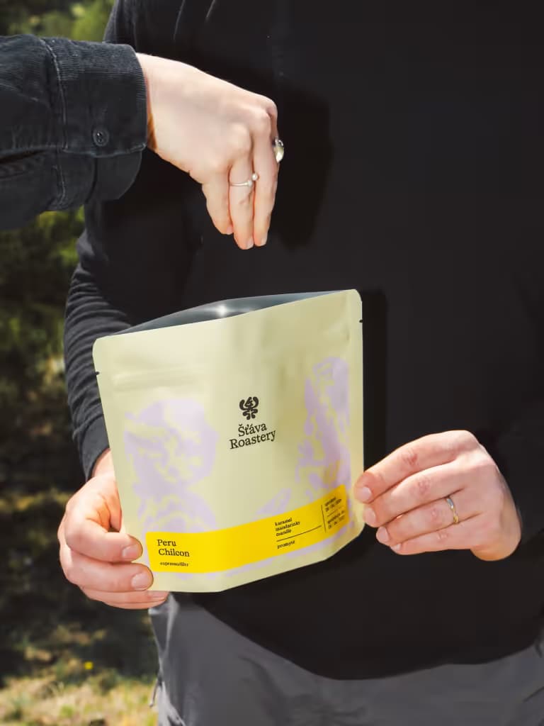 Balení kávy Šťáva Roastery držené venku na slunci
